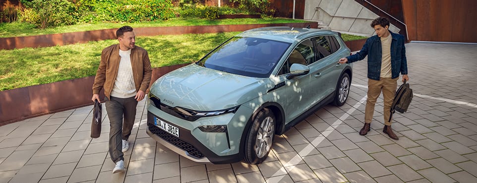 Zwei Geschäftsleute steigen in einen elektrischen Škoda