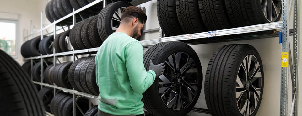 Servicetechniker lagert Kompletträder im Reifenregal ein